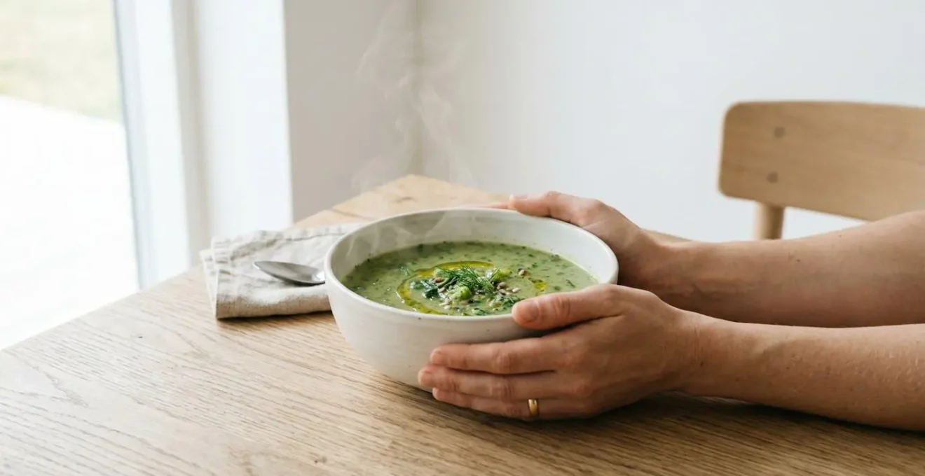 Vue minimaliste d'un bol de soupe de légumes verts fumante créant une sensation de plénitude réconfortante